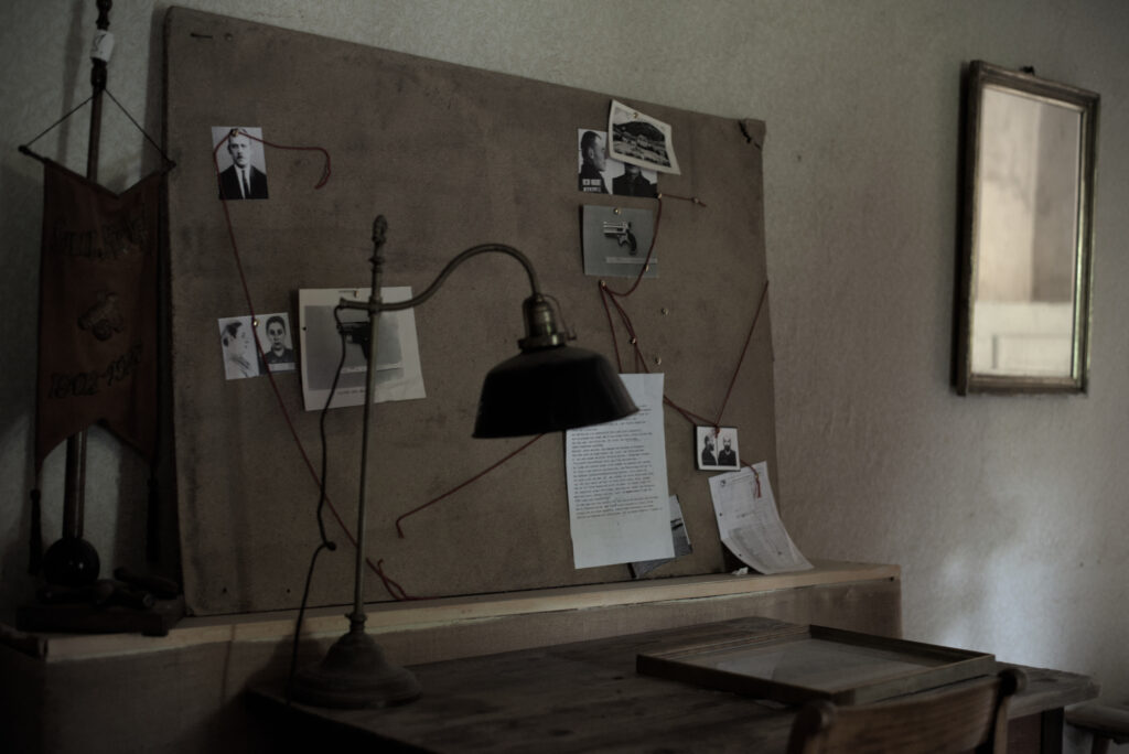 Auf einem Schreibtisch steht eine alte Schriebtischlampe. Daneben liegt ein Bilderrahmen