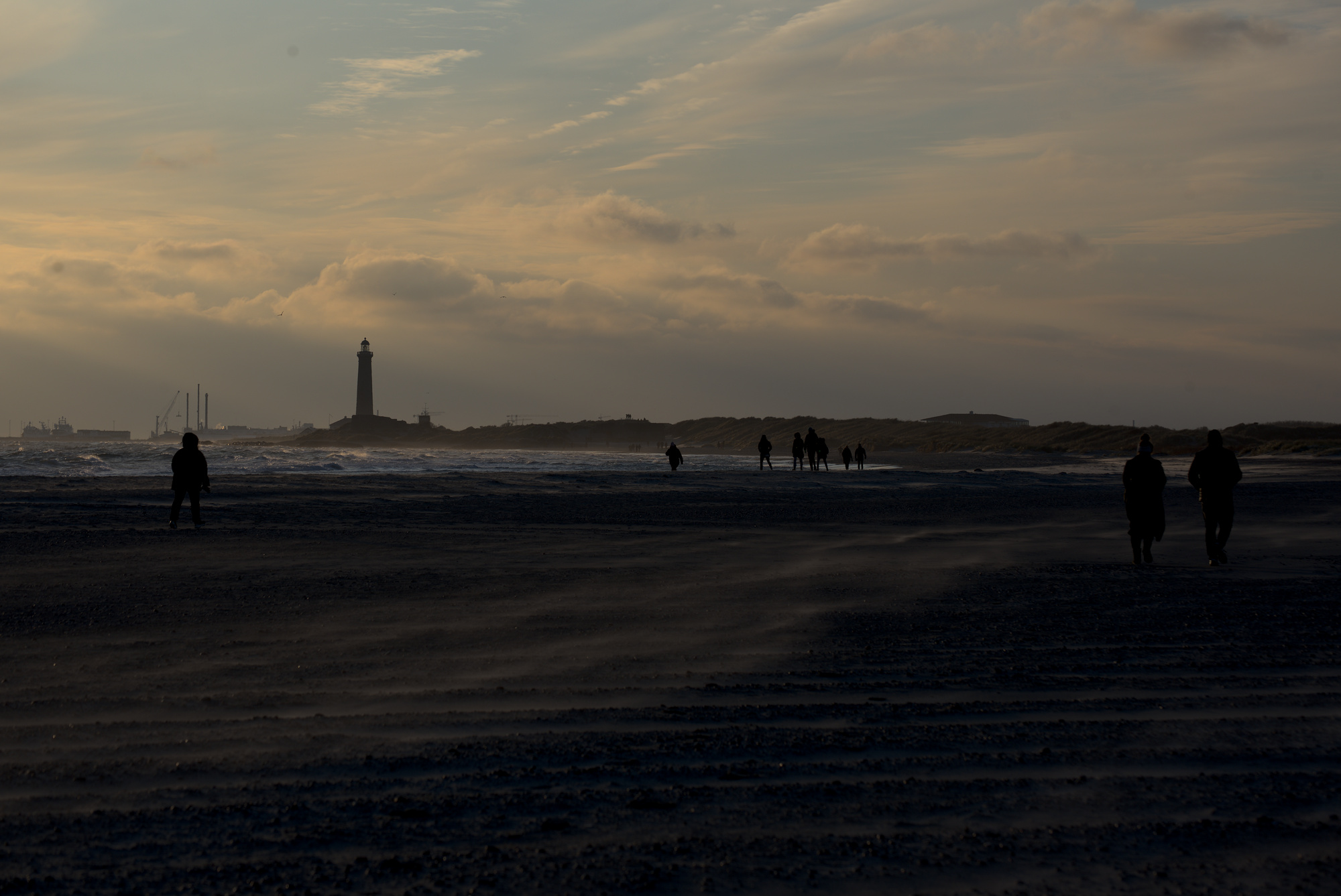 Strand und Meer am Horizont sind Dünen und ein Leuchtturm